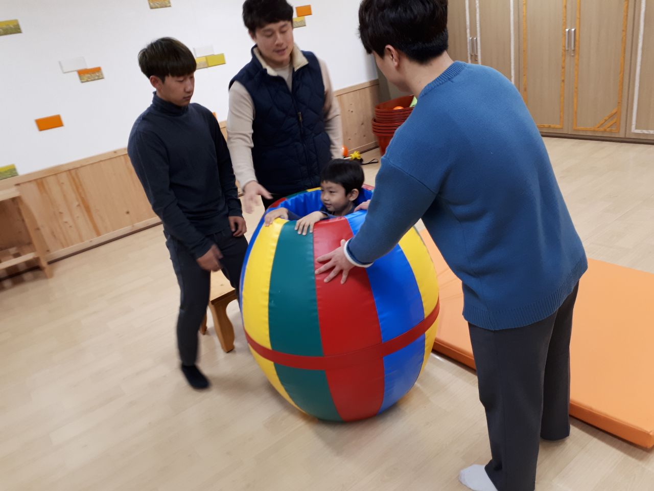 원형 심리치료 놀이기구에 있는 남자아이와 그걸 지켜보는 세 남성