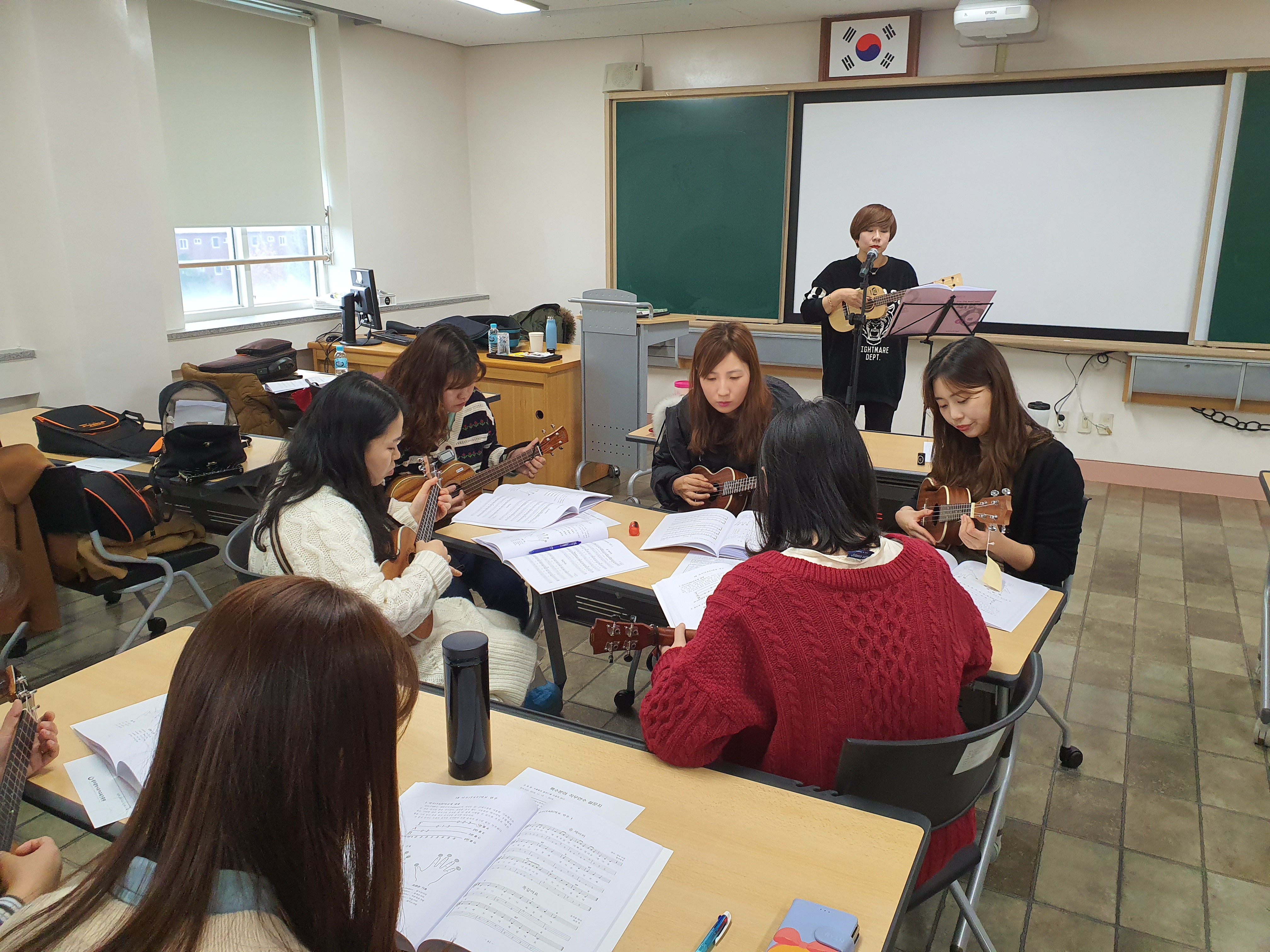 모여서 우쿨렐레 연습하는 선생님들과 앞에서 설명하는 우쿨렐레강사